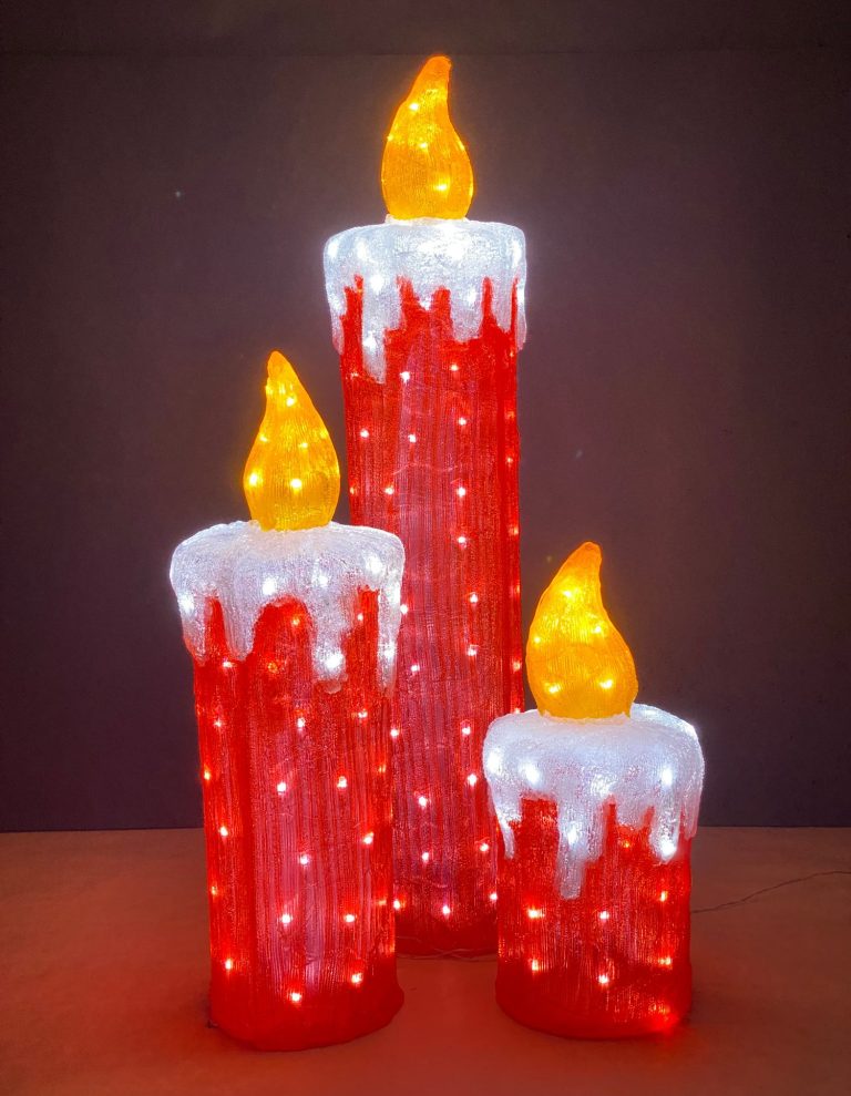 Drei leuchtende Weihnachtskerzen in Rot und Weiß mit flackernden Spitzen.