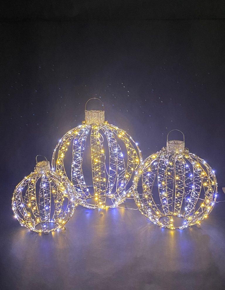 Drei leuchtende draht-Kugeln mit Perlenketten in Gelb und weiß vor schwarzem Hintergrund.